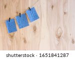 Small photo of blue craft sheets on black clothespins hang on a thread on a wooden background