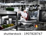 Small photo of Professional chef in white uniform salts king prawns. Wooden salt grinder