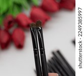 Small photo of 2 brushes in hand. Close-up of a flat brush for blending and an eyeshadow brush. deluxe shader.
