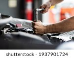 Small photo of Caucasian male mechanic repairs car in garage. Car maintenance and auto service garage concept. Closeup hand and spanner.