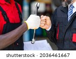 Small photo of Auto mechanic with wrench in hand. stranglehold. Closeup car repair black man hand and caucasian man customer.