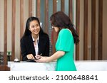 Small photo of Friendly receptionist woman working at desk in hotel lobby. Leisure and travel at holidays.
