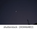 Small photo of waning moon on blue night sky from afar