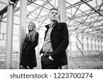 Small photo of the boy and the girl stand apart from each other against the background of urban iron structures. Black and white photo