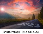 road on which is written 2023 at sunrise in the mountains .beginning of 2023 morning fog near the forest and mountains and the road. beautiful sky. concept of the road to ecology.