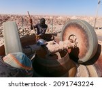 Small photo of Chami, Mauritania - January 20, 2019: artisanal gold miner crushing high grade ore in a basic crusher before using mercury to extract gold.