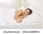 Small photo of Tranquil Caucasian woman sleeping alone on side with hands under cheek. Pretty brunette european lady enjoying good night's rest in comfortable bed on soft pillow and natural organic cotton bedclothes