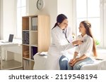 Smiling doctor checking child's lungs during medical checkup in modern sunny exam room at the clinic. Friendly female pediatrician using stethoscope to examine breathing and heartbeat of young patient