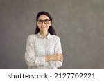 Small photo of Happy confident smiling caucasian woman looking at camera studio headshot portrait. Casual positive lady showing cheerful emotion sanding on grey background. Feminine and youth, people expression