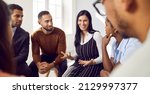 Small photo of Female coach or team leader tells funny story or joke to diverse team during work meeting. Multiracial employees sitting in circle on chairs during informal brainstorming exchange ideas.