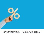Percentage sign in human hand. Entrepreneur, client, customer holding percent symbol on blank solid blue text copyspace background. Business, finance, investment, tax increase, value added tax concept