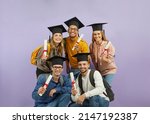 Small photo of Group of happy diverse mixed race multiethnic students with backpacks, in mortarboard graduate hats holding diploma scrolls, looking at camera and smiling. University education and graduation concept