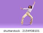 Small photo of Overjoyed African American teen girl in fashionable clothes dance on violet studio background. Funny black teenage young woman have fun make dancer moves. Hobby and entertainment.