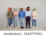 Small photo of Funny half people half animals waiting by office wall together. Group portrait company workers, students or job applicants wearing extravagant wacky absurd comedy fancy dress carnival masquerade masks