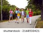 Small photo of School friendship. Funny schoolchildren group with backpacks have fun walking together on path in park. Cheerful boys and girls in summer casual clothes return home from school lessons together.