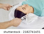 Small photo of Sound healing specialist working with female patient. Man holding two metal tuning forks near young woman's head. Healer's hands close up. Holistic relaxation, music therapy, stress reduction concept