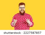 Portrait of funny happy joyful charismatic fat bearded man in polka dot shirt and eyeglasses smiling and pointing his index fingers at camera as if saying Let's have fun or Exactly, I agree with you