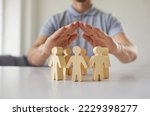 Close up employer holding hands over little pawn people. Responsible corporate business manager protects employees, guards their interests and creates equal and safe environment for developing talents