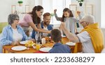 Small photo of Cheerful family enjoying meal, eating chicken and having fun together. Happy beautiful mother is serving food for dad, grandma, grandpa and children sitting around festive table at home