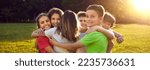 Small photo of Happy friends hugging in green summer park. Group of children having fun together. Bunch of cheerful little kids smiling and hugging each other tight. Outdoor shot with sun flare. Banner background