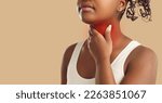Small photo of Sore throat pain. Cropped image close up of unknown young dark skinned woman holding her throat while standing on beige background near copy space. Painful area is highlighted in red. Banner.