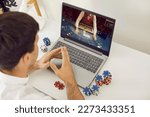 Small photo of Online casino. Young smart male online poker player relaxing gambling on his laptop computer at home. Concept of online gambling, win money, sports bet, chance, succeed, fortune and addiction.