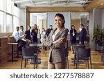 Small photo of Happy professional business teacher after corporate training class for team of workers. Beautiful young woman in suit jacket standing in office conference room, looking at camera and smiling