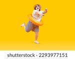 Funny happy overweight woman having fun on summer holiday. Cheerful joyful fat girl in Tshirt, shorts, beach floater ring, sun hat and sunglasses dancing isolated on yellow background Vacation concept