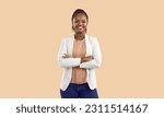 Small photo of Studio shot of happy confident young black businesswoman. Portrait of smiling good looking African American business lady in white jacket standing with arms folded isolated on solid beige background