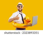 Adult bearded corporate office worker man in shirt, summer holiday sun glasses, funny inflatable beach rubber duck pool swim ring work on laptop PC show thumbs up sign gesture yellow studio background