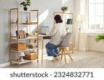 Small photo of Remote accountant working on a laptop. Back view of a fat, large, stout woman sitting at her cozy desk at home, using her notebook computer, and working with business spreadsheets