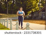 Small photo of Happy overweight woman jogging in park. Smiling motivated beautiful fat large plump stout lady in sports top bra and yoga pants running on paved park path on sunny morning or evening. Fitness concept
