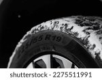 Close up view of snowy tire with tire width, height and wheel diameter designation. Winter tire size types labels.