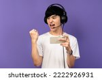 Young Asian man standing on violet background Using a mobile phone.