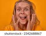 Small photo of Young overjoyed Caucasian woman with freckles screams loudly and waves arms experiencing delight and influx of positive emotions that improve mood and induce state of euphoria on yellow background.