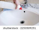 Removal of blockage in the sink, the hand of a man with a bottle of a special remedy with granules. Clean the blockages in the bathroom with chemicals. High quality horizontal photo