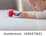 Baby with rattle in hand. Cute baby playing with colorful rattle education toy. Family, new life, childhood, beginning concept. Little baby girl taking rattle