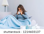 Sick Woman.Flu.Woman Caught Cold. Sneezing into Tissue. Headache. Virus .Medicines. Young Woman Infected With Cold Blowing Her Nose In Handkerchief. Sick woman with a headache sitting on a sofa 