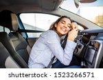 Young and cheerful woman enjoying new car hugging steering wheel sitting inside. Woman driving a new car. Woman Driver Portrait at Car