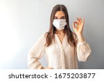 Young woman wearing medical face mask, studio portrait. Woman Wearing Protective Mask and Showing OK sign. Woman wearing surgical mask for corona virus