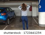 Rear View Of A Shocked Woman Standing In Parking Lot After her Car Was Stolen. Car missing. Woman returned after shopping and didn't find her car on underground parking