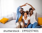 Happy family forming house roof with their hands at home. Insurance concept. Concept of housing and relocation. happy family mother father and kids with roof at home