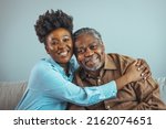 Small photo of Loving father and daughter together on sofa. Beautiful woman with her father as they both smile. Beautiful young woman embracing her father. Senior African American man and daughter