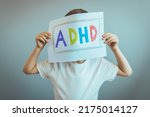 Small photo of Young boy holds ADHD text written on sheet of paper. ADHD is Attention deficit hyperactivity disorder. Close up. Boy holding paper and admitting suffering from ADHD.