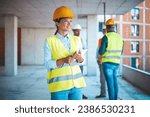 Small photo of Female construction engineer is using digital tablet on the construction site. Young female worker using her digital tablet at a construction site. Woman with plan, digital tablet.