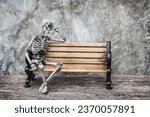 Skeleton ghost sits sleepily on a an old bench with dark background gothic or loft style.