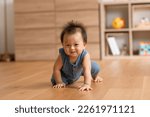 Small photo of Healthy asian baby toddler crawling on floor to learn to crawl indoors. Adorable baby keeping her belly and legs down on the floor to belly crawl fun and happiness at home