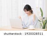 Small photo of A young woman doing a guts pose while using a laptop in the room
