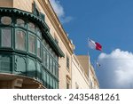 Small photo of A green Gallarija, a typical element of Maltese vernacular architecture, with Maltese flags blowing in the wind, Valletta, Malta