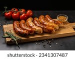 Small photo of German cuisine. Juicy fried chicken, beef and pork sausages lie on a wooden board, on a black background.